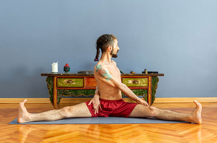 A man is doing Upavistha Konasana or wide-angle forward sitting - Emoha